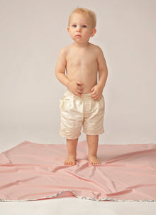  Toddler in white shorts stands on pink blanket with floral trim